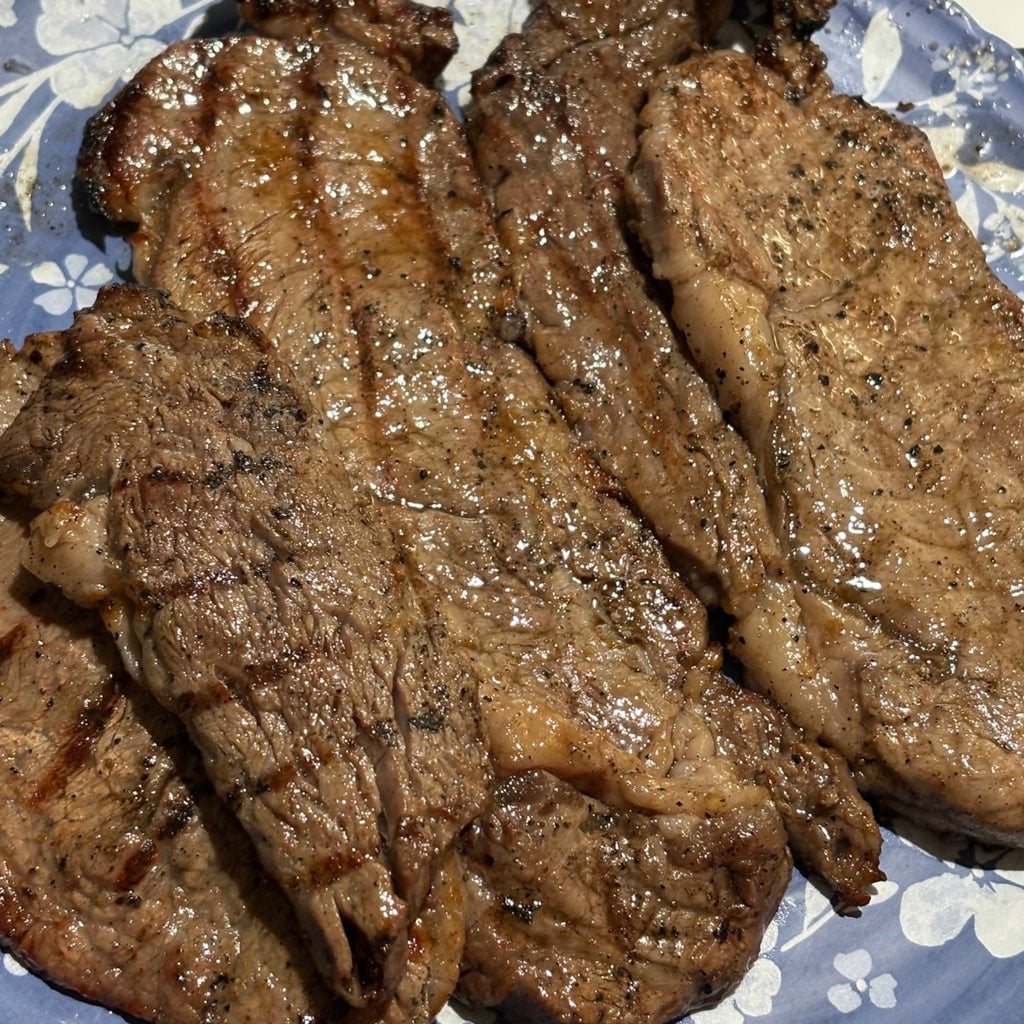 Grilled Ribeyes meat slices on a blue floral-patterned plate. 2-in-1 Steak Seasoning & Meat Tenderizer