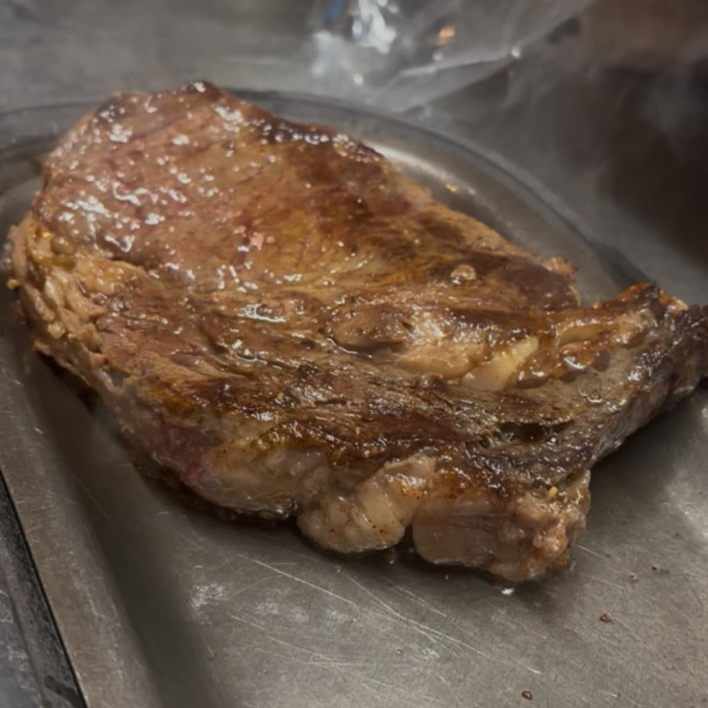 Grilled steak on a metal plate. 2-in-1 Steak Seasoning & Meat Tenderizer