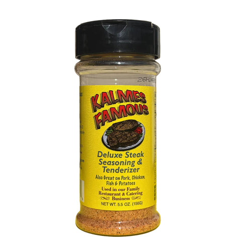 A bottle of Kalmes Famous Deluxe Steak Seasoning & Tenderizer, 5.5 oz, featuring a bright yellow label and a black cap, set against a yellow cloth and a light wood paneled background.